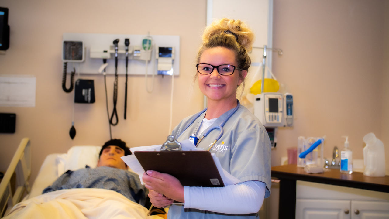 Nurse holding clipboard in hospital patient room